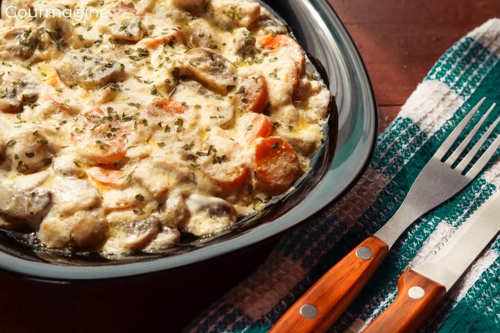 A black plate filled with mushrooms and carrots in sour cream