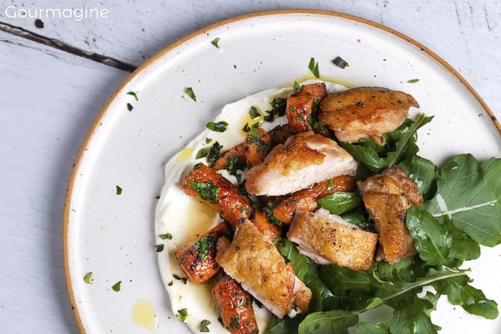 Pouletstücke, Rüebli und Rucola angerichtet auf einem Joghurt-Bett auf einem weissen Teller