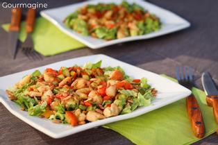 Two square plates with fried chicken, pieces of pepperoni and green salad leaves