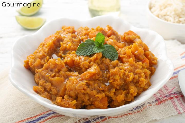 A white bowl filled with an orange vegetable lentils curry