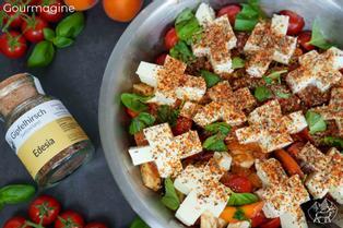 Metal bowl with a mixture of mozzarella, tomatoes, apricots and basil leaves covered in spices and next to a small Gipfelhirsch glass bottle with spices