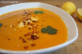 A white bowl filled with sweet potato soup and chicken pieces