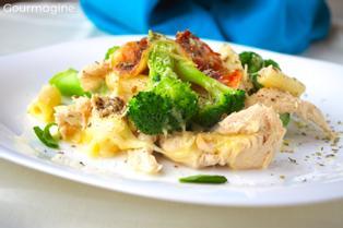 Baked penne, broccoli, chicken and cheese served on a white plate