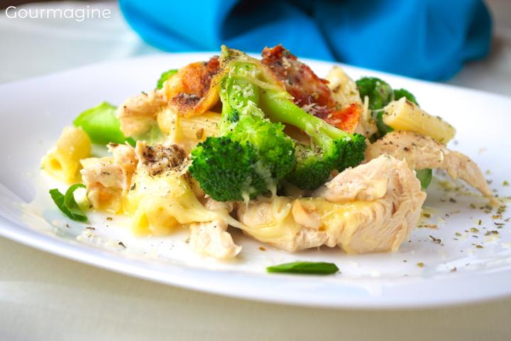 Baked penne, broccoli, chicken and cheese served on a white plate