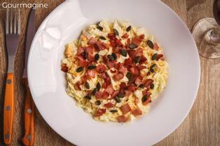 Ein weisser Teller gefüllt mit Kabis-Salat, Speckwürfelchen und Kürbiskernen