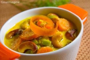 Eine orange-weisse Schüssel gefüllt mit Rüebli, Lauch, Pastinaken und Cashewnüssen in einer Currysauce