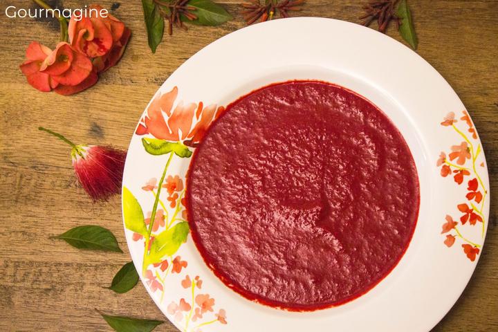 Ein verzierter weisser Teller gefüllt mit Curry-Randen-Suppe und dekorativen Rosenblättern