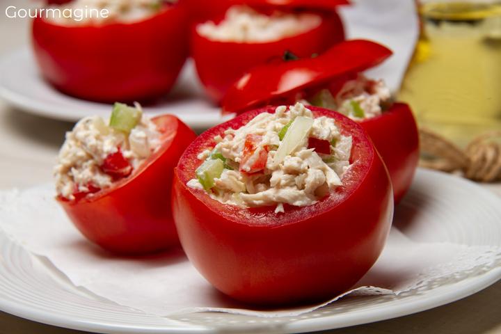 Drei Tomaten gefüllt mit einer Poulet-Peperoni-Joghurt-Mischung und angerichtet auf einem weissen Teller