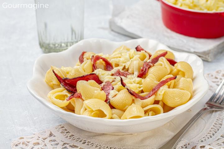 A white plate filled with elbow pasta, strips of fried cured beef and grated Appenzell cheese