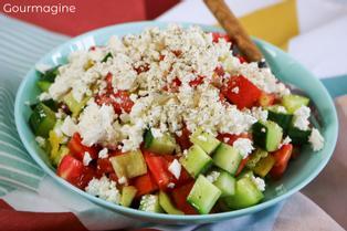 Eine grüne Schüssel gefüllt mit Gurken, Tomaten, Peperoni und Käse