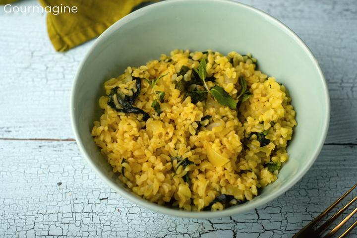 Cooked bulgur and spinach served in a grey-blue bowl