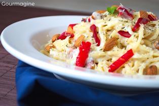 Spaghetti with peppers and almonds served on a white plate